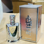 Silver perfume bottle and packaging with intricate design on a wooden surface