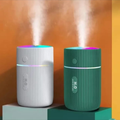 Two humidifiers, one white and one green, emitting mist against an orange background.