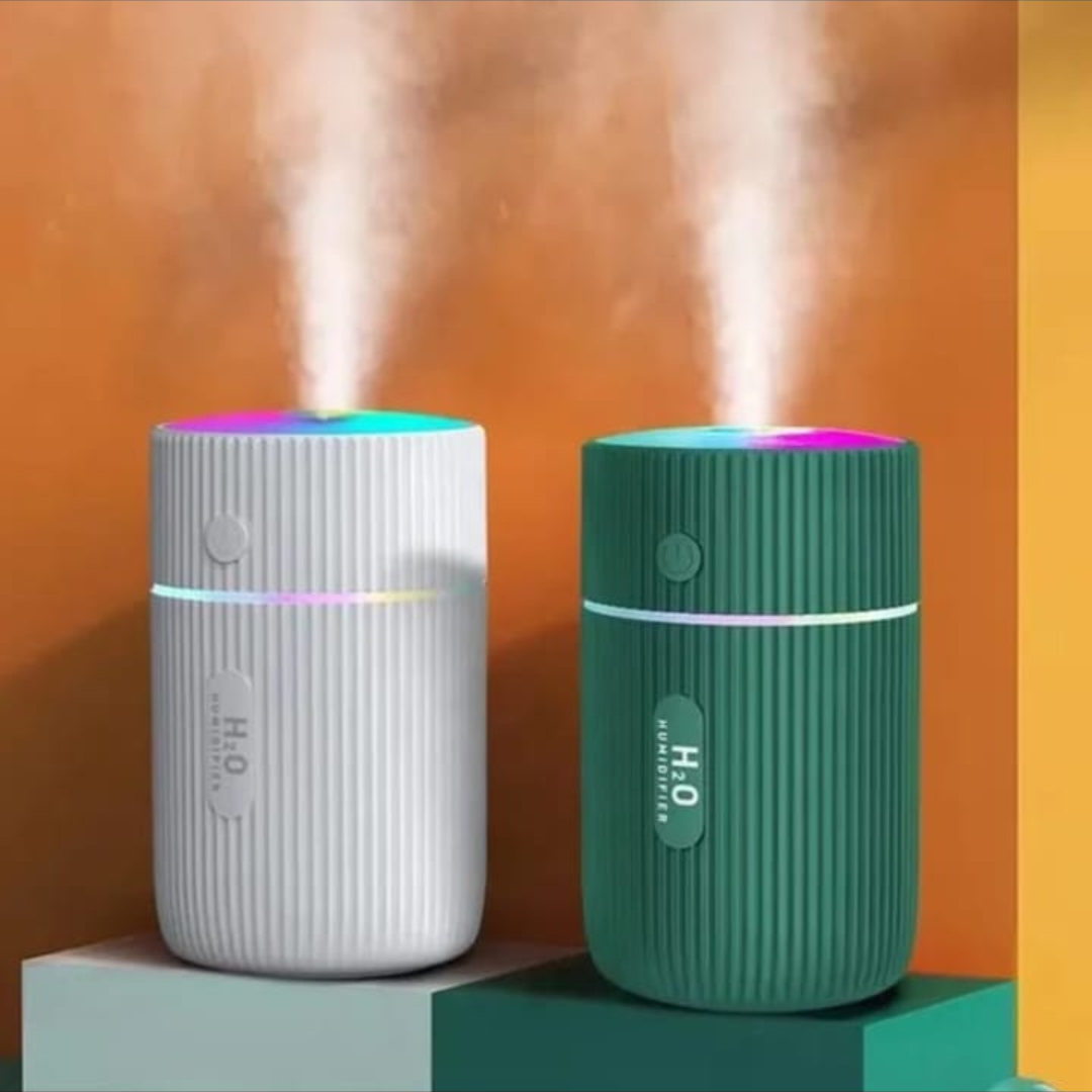 Two humidifiers, one white and one green, emitting mist against an orange background.