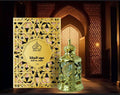 Gold perfume bottle and packaging with intricate design against a warm-toned architectural background